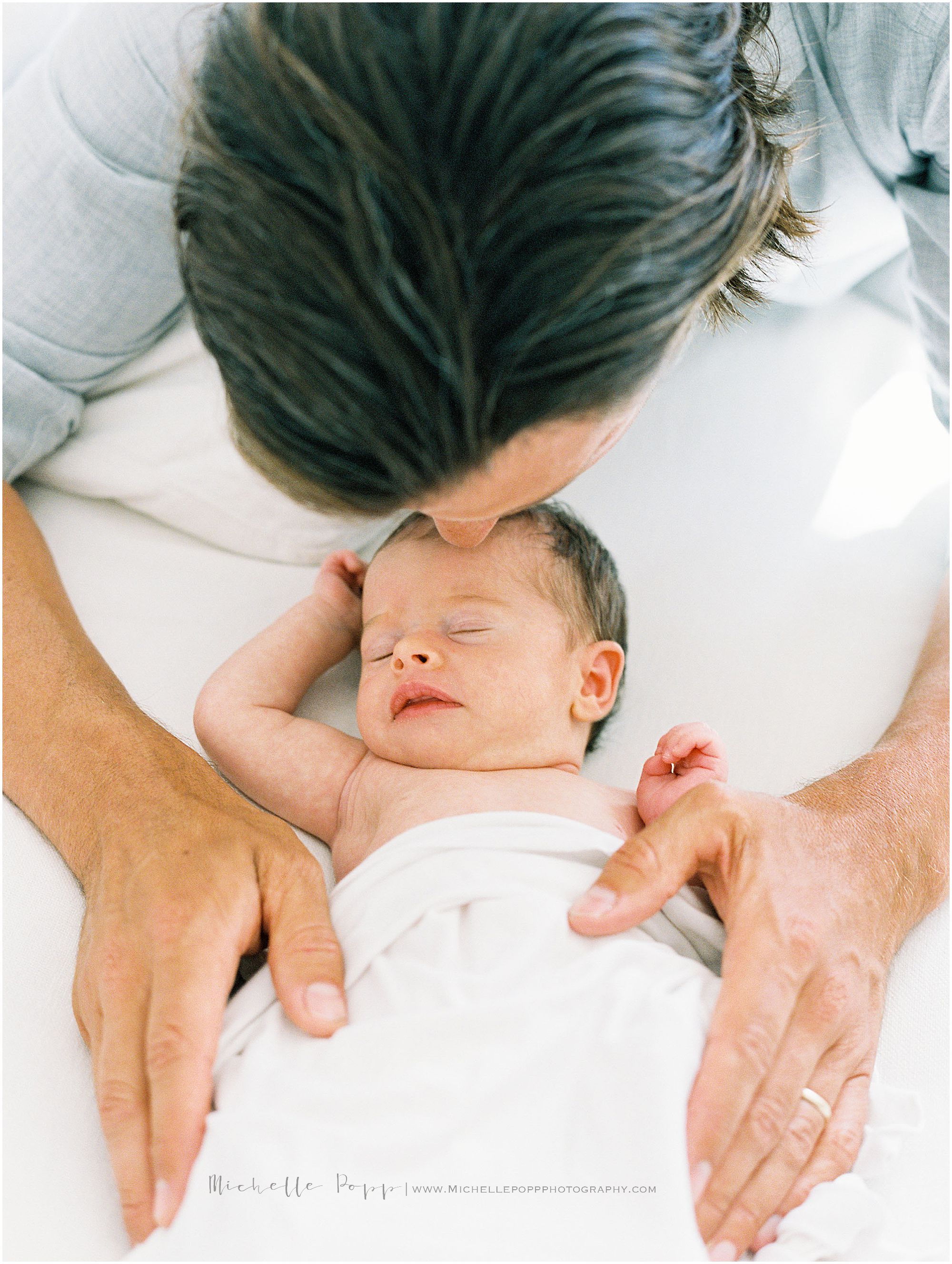 dad kissing newborn baby on head in La Jolla home 