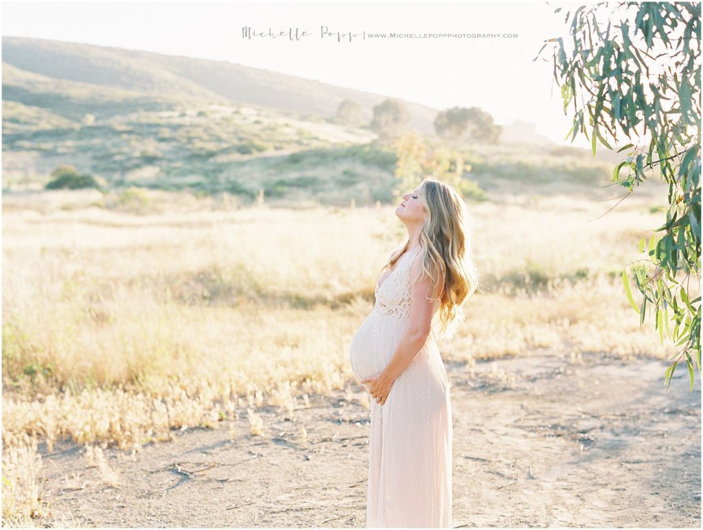 mom holding baby bump on field