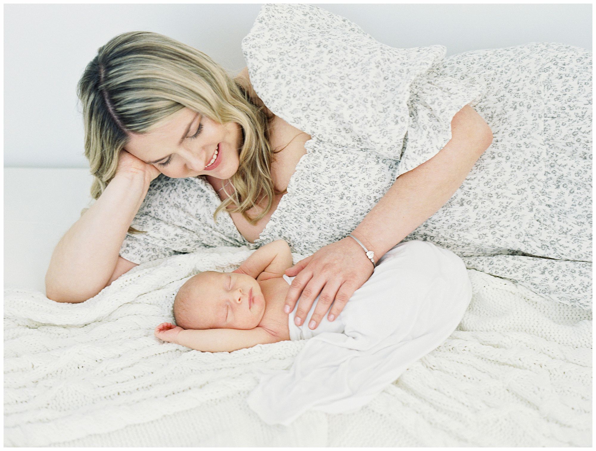 mom and newborn baby snuggling on bed